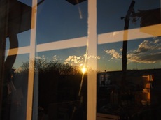 磨いたガラスに映る沈む太陽　テーブルの向こうの棚に夕日が当たり.jpg